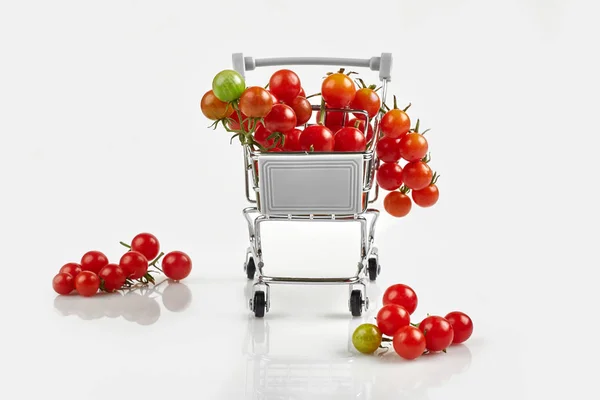 Mini carrello pieno di pomodorini ciliegia su sfondo bianco — Foto Stock