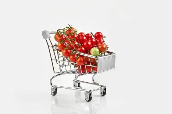 Mini carrinho de compras cheio de tomate cereja no fundo branco — Fotografia de Stock