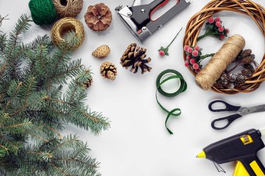 Noel ve yeni yıl tatil için hazırlanıyor. Düz-lay kürk ağaç dalları, çelenk, ip, makas, Kraft kağıt üzerinde beyaz masa arka plan, üstten görünüm.