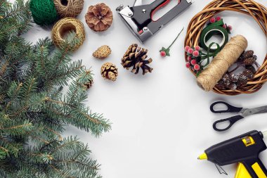 Noel ve yeni yıl tatil için hazırlanıyor. Düz-lay kürk ağaç dalları, çelenk, ip, makas, Kraft kağıt üzerinde beyaz masa arka plan, üstten görünüm.
