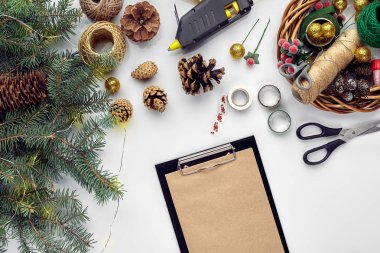 Noel ve yeni yıl tatil için hazırlanıyor. Düz-lay kürk ağaç dalları, çelenk, ip, makas, Kraft kağıt üzerinde beyaz masa arka plan, üstten görünüm.