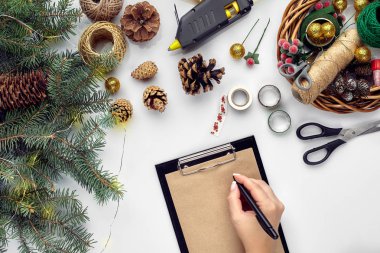 Noel ve yeni yıl tatil için hazırlanıyor. Düz-lay kürk ağaç dalları, çelenk, ip, makas, Kraft kağıt üzerinde beyaz masa arka plan, üstten görünüm.