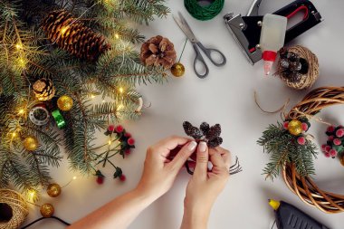 Eller Noel çelenk kırmızı berry ve orman koniler ile çam dalları ile süsleyin. Beyaz arka plan. Yeni yıl kavramı.