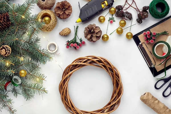 Preparando para o Natal ou feriado de Ano Novo. Flat-lay de ramos de árvores de pele, grinaldas, corda, tesoura, papel artesanal sobre fundo de mesa branca, vista superior . — Fotografia de Stock