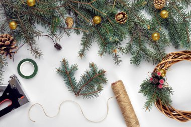Yaratıcı noel numarası. Kadın el yapımı Xmas çelengi yapıyor. Ev eğlencesi, aletler, ıvır zıvır ve beyaz masa arka planında tatil süslemeleri için ayrıntılar. Üst Manzara. Noel ya da Yeni Yıl tatiline hazırlanılıyor