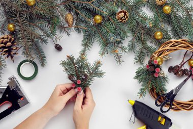 Eller üstten görünüm olun Noel çelenk. Yemeği hediyeler ve verilirse, şube ve beyaz masa üstünde alet çeki düzen vermek.