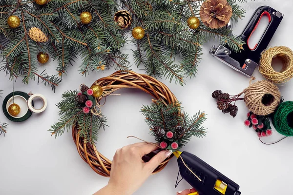 Eller Noel çelenk kırmızı berry ve orman koniler ile çam dalları ile süsleyin. Beyaz arka plan. Yeni yıl kavramı.