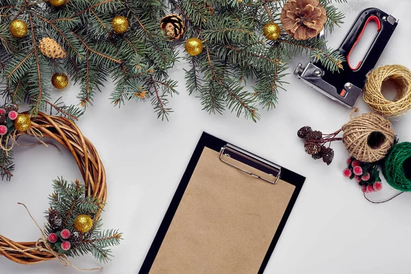 Natal criativo diy. Mulher fazendo grinalda de Natal artesanal. Casa lazer, ferramentas, bugigangas e detalhes para decorações de férias no fundo da mesa branca. Vista superior — Fotografia de Stock