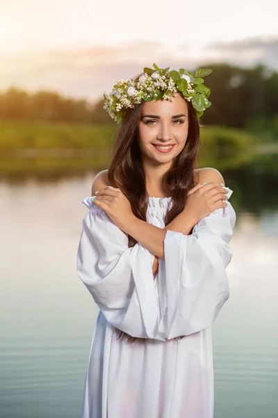 Woman in white dress in the water. Art Woman with wreath on her head in river. Wreath on her head, Slavic traditions and paganism
