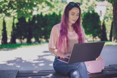 Genç kız ahşap üzerinde oturan bahar parkta okuyor