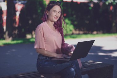 Genç kız ahşap üzerinde oturan bahar parkta okuyor