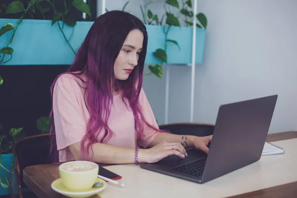 年轻妇女与粉红色头发与膝上型电脑坐在咖啡馆, — 图库照片
