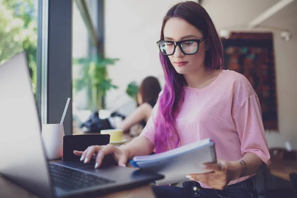 Side view of young businesswoman sitting at table in coffee shop