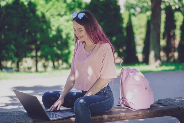 Молодая девушка учится в весеннем парке, сидит на деревянном — стоковое фото
