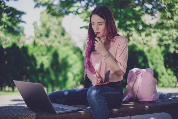 Femme écrivant dans un cahier assis sur un banc en bois dans le pair — Photo