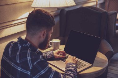 Genç adam kafede iş molası sırasında net-kitap yolu ile sohbet