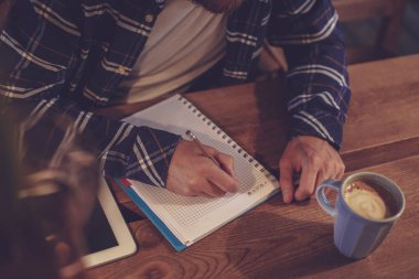 Genç işadamı oturur kafe, tablo ve yazıyor ev sakallı