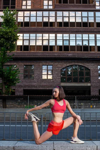 Mulher desportiva alongamento e aquecimento pernas antes de correr treino de fitness urbano. Esporte e conceito de estilo de vida saudável . — Fotografia de Stock