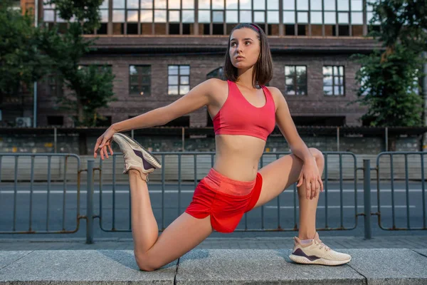 Спортивна жінка розтягує і розігріває ноги перед тренуванням міського фітнесу. Спорт і концепція здорового способу життя . — стокове фото
