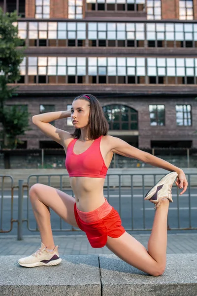 Mulher desportiva alongamento e aquecimento pernas antes de correr treino de fitness urbano. Esporte e conceito de estilo de vida saudável . — Fotografia de Stock