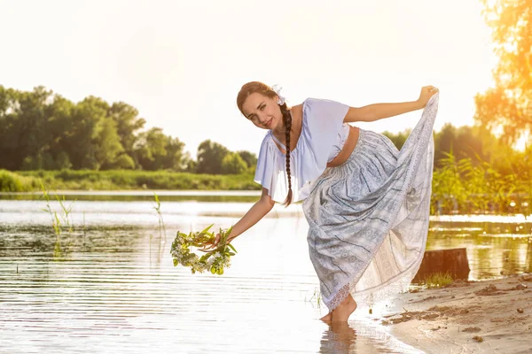Mulher branca bonita nova que está na margem do rio. Imagem rural tradicional com menina em primeiro plano e espaço de cópia. Inflamação solar — Fotografia de Stock