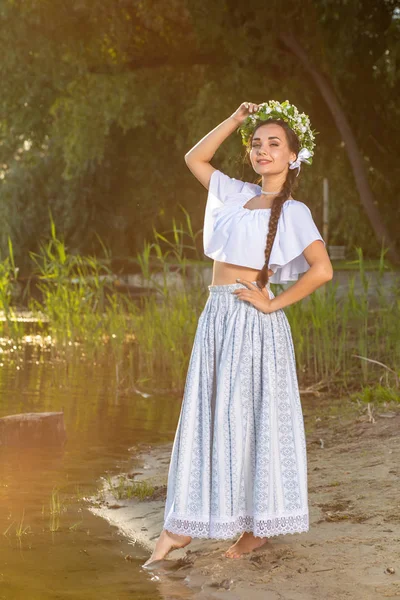 Junge schöne Kaukasierin, die am Ufer des Flusses steht. traditionelles Landbild mit Mädchen im Vordergrund und Kopierraum. — Stockfoto
