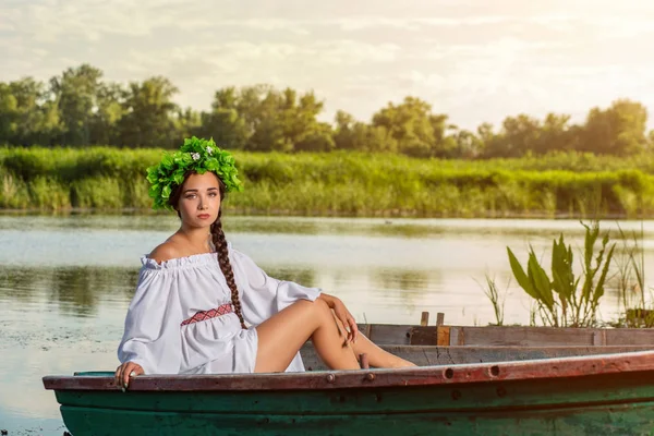 Fiatal szexi nő, a hajó a naplemente. A lánynak a virág koszorú a fején, pihentető és vitorlás folyó. Fantasy art photography. — Stock Fotó