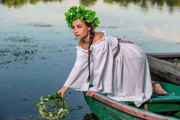 Fiatal szexi nő, a hajó a naplemente. A lánynak a virág koszorú a fején, pihentető és vitorlás folyó. Fantasy art photography. — Stock Fotó