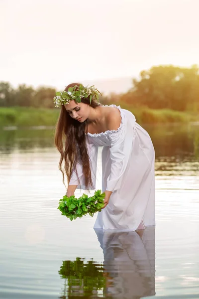 Woman in white dress in the water. Art Woman with wreath on her head in river. Wreath on her head, Slavic traditions and paganism