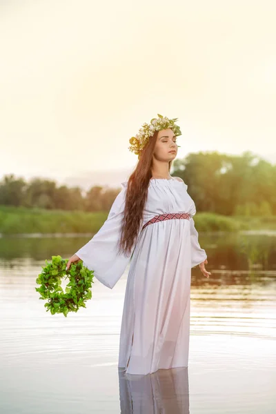 Woman in white dress in the water. Art Woman with wreath on her head in river. Wreath on her head, Slavic traditions and paganism