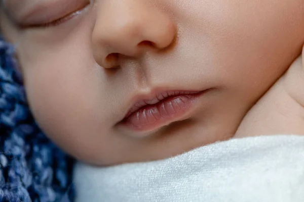 Pasgeboren baby - baby, gezicht close-up. De slapende pasgeboren jongen onder een witte deken van gebreide ligt op de blauw bont. — Stockfoto