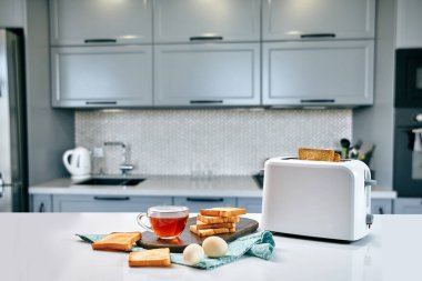 Rahat mutfakta kahvaltı. Yararlı ve lezzetli yemekler. Çay ve tost ekmek kızartma makinesi, yumurta içinde.