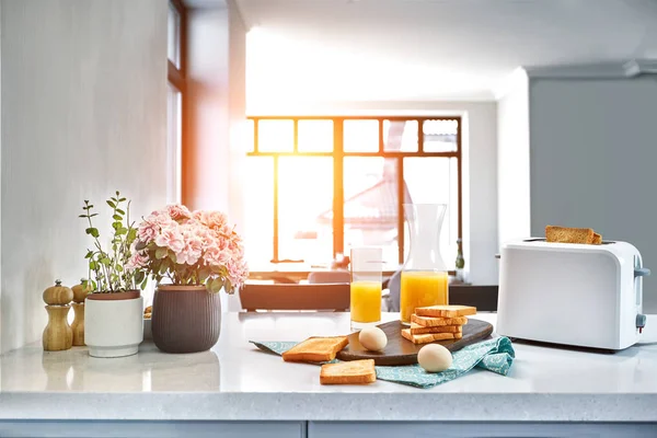 Toaster mit frischem Toast, Eiern und einem Glas Orangensaft auf einem hellen Küchentisch. Sonneneruption — Stockfoto