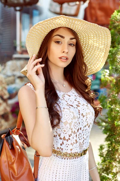 Fiatal stílusos nő az utcán, divatos ruhában, szalma kalap, utazás a hátizsák viselése. — Stock Fotó