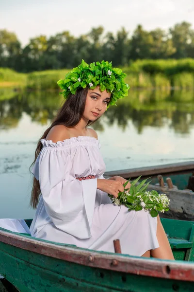 A nimfa a hosszú, sötét haj, egy fehér vintage ruha a folyó közepén egy csónakban ül. — Stock Fotó