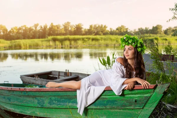A nimfa a hosszú, sötét haj, egy fehér vintage ruha a folyó közepén egy csónakban ül. — Stock Fotó