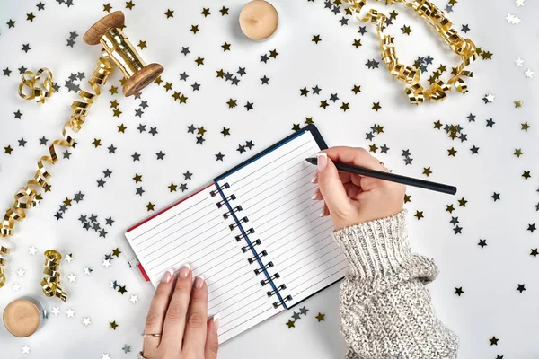 Sváteční ozdoby, jemné vlnovkou stuhy, kovová hvězda ve tvaru konfety a notebook s seznamu přání na bílém stole, ploché rozložení styl. Vánoční svátky dekorace koncept. — Stock fotografie