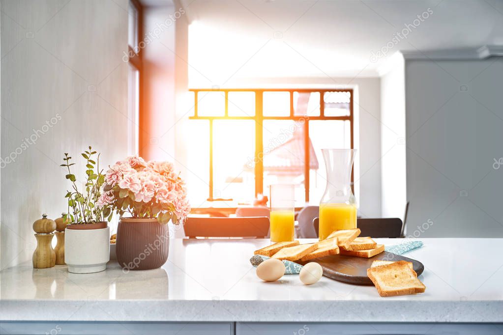 Portion of toasts on a wooden board with orange juice. Breakfast is served on a table with light blue napkin.