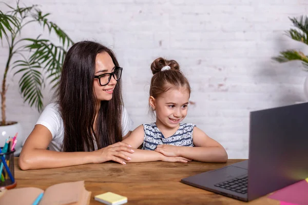 Uma jovem mãe com filhinha está comprando na Internet no computador pessoal — Fotografia de Stock