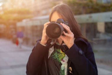 Çekici turist kadın fotoğrafçı ile fotoğraf makinesi, şehirde sokak açık. Güneş parlaması