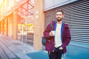 Kahve içme mor kış ceket yakışıklı genç adam. Adam sokakta kahve içme. Güneş parlaması