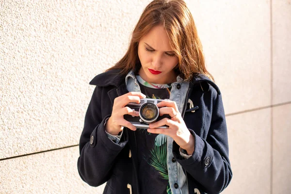 Happy hipster girl making photo with retro camera on city street — Stock Photo, Image