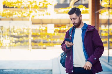 Açık düşmek veya yakışıklı hipster kış portre sakal, beyaz tişört, mavi gömlek ile adam ve akıllı telefon tutarak ceket Bordo