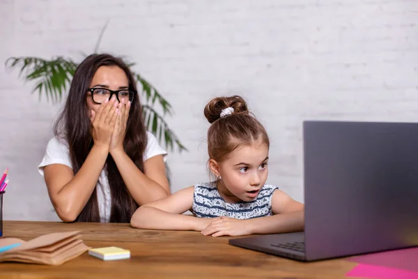 Uma jovem mãe com filhinha está comprando na Internet no computador pessoal — Fotografia de Stock