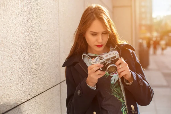 Menina hipster feliz fazendo foto com câmera retro na rua da cidade. Inflamação solar — Fotografia de Stock