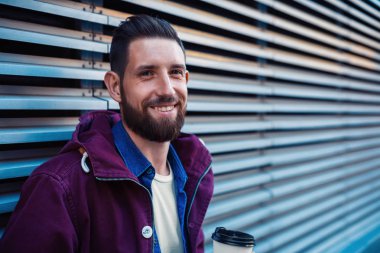 Açık düşmek veya yakışıklı hipster kış portre sakal, beyaz tişört, mavi gömlek ile adam ve sıcak kahve tutan ceket Bordo.