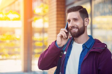 Açık düşmek veya yakışıklı hipster kış portre sakal, beyaz tişört, mavi gömlek ile adam ve akıllı telefon tutarak ceket Bordo
