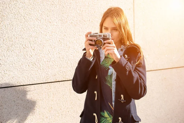 Gelukkig hipster meisje foto met retro camera op stad straat maken. Zon flare — Stockfoto