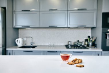 Güneşli sabah kahvaltı mahallinde. Mutfak masasında bisküvi ile şeffaf siyah çay kupa