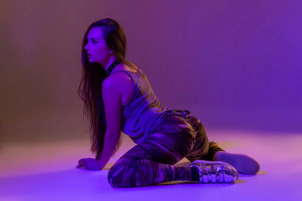 Attraktiv ung brunette kvinde i studiet danser røv dans på en mørk baggrund - Stock-foto